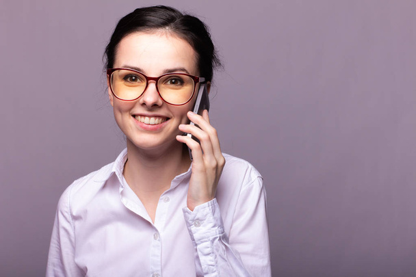 beautiful girl in a white shirt and glasses for vision communicates on the phone - Foto, Bild