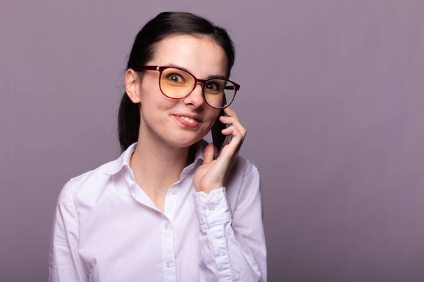 girl in a white shirt and glasses communicates on the phone - Photo, Image