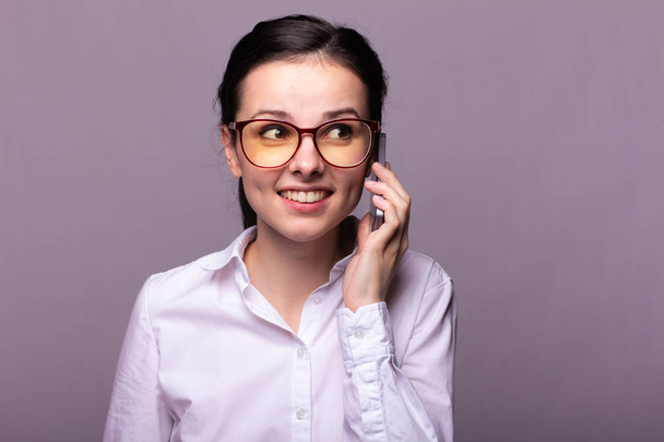 beautiful girl in a white shirt and glasses for vision communicates on the phone - Foto, immagini