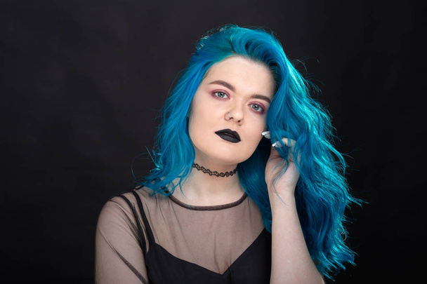 people, fashion and hair concept - close-up portrait of young woman in black dress with blue hair on black background - Photo, image