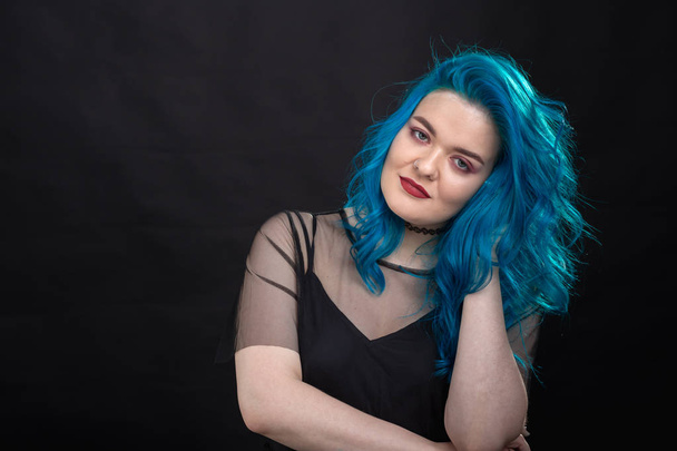 Estilo y concepto de moda - Mujer joven y atractiva con el pelo azul posando sobre fondo negro
 - Foto, Imagen