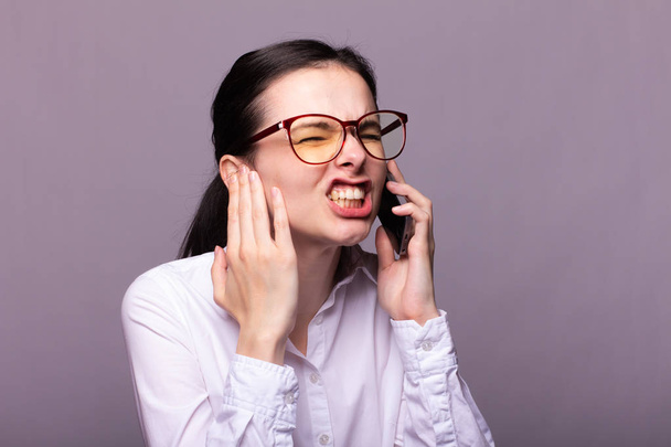 girl in a white shirt and glasses communicates on the phone - 写真・画像