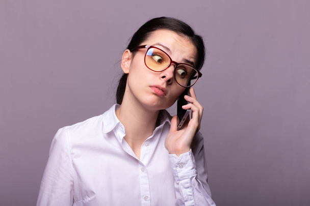 girl in a white shirt and glasses communicates on the phone - Foto, afbeelding