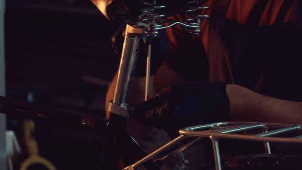 thème petite entreprise réparation de vélo. Un jeune homme brune caucasien portant des lunettes de sécurité, des gants et un tablier utilise un outil à main pour réparer et ajuster le vélo dans le garage de l'atelier
 - Photo, image