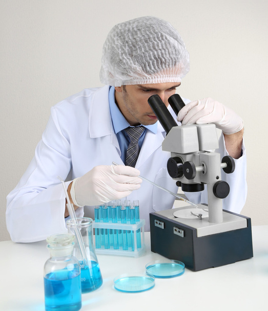 Young laboratory scientist looking at microscope in lab - Foto, imagen