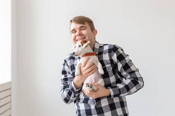 people, pets and animals concept - handsome man holding jack russell terrier puppy on white background - Photo, Image
