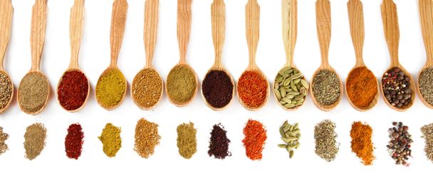 Assortment of spices in wooden spoons, isolated on white - 写真・画像