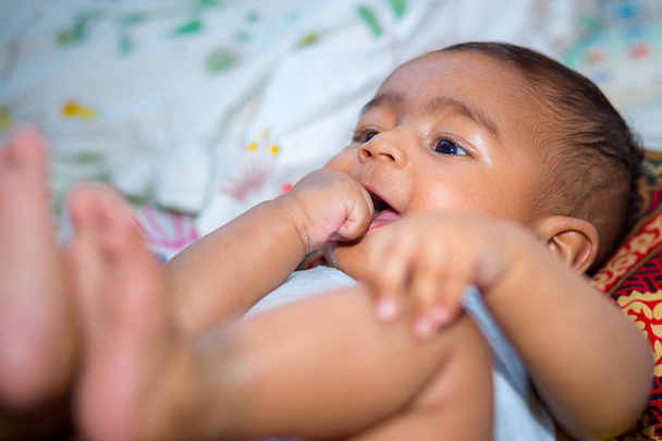 Ένα χαμογελαστή μωρό ρουφάει το δάχτυλό της. - Φωτογραφία, εικόνα