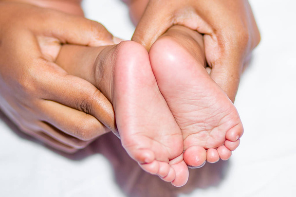 Egy anya Holding baba két lába fehér alapon. - Fotó, kép