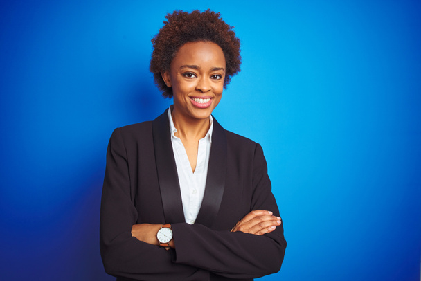 African American Business Executive kobieta nad białym tle niebieski szczęśliwy twarz uśmiechnięty z skrzyżowanymi ramionami patrząc na aparat fotograficzny. Osoba pozytywna. - Zdjęcie, obraz
