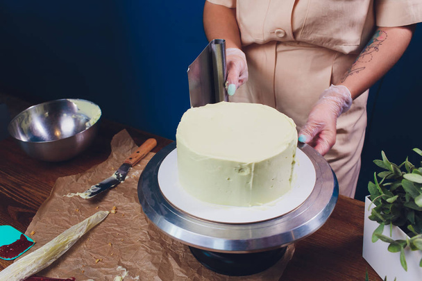 женские руки делают печенье торт с белым кремом с помощью приготовления лопатки
. - Фото, изображение