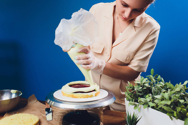womens hands making biscuit cake with white cream using a cooking spatula. - Valokuva, kuva