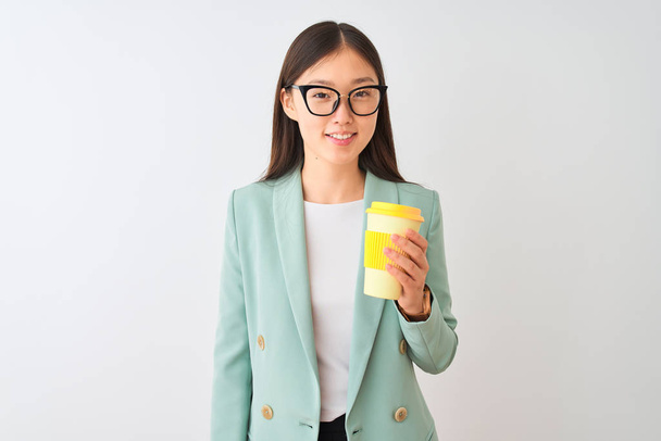 Młoda Chińska kobieta nosi okulary picia Coffe na białym tle z szczęśliwą twarzą w twarz i uśmiechając się z pewnym uśmiechem, pokazując zęby - Zdjęcie, obraz