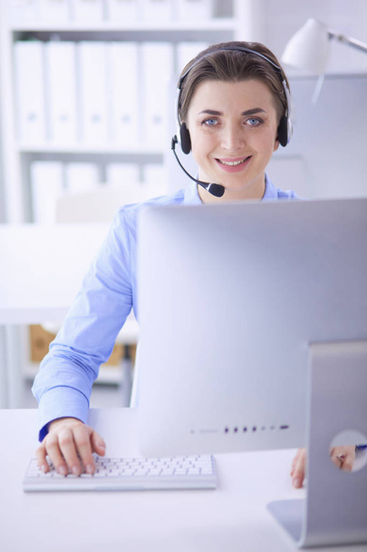 Serious pretty young woman working as support phone operator with headset in office - Zdjęcie, obraz