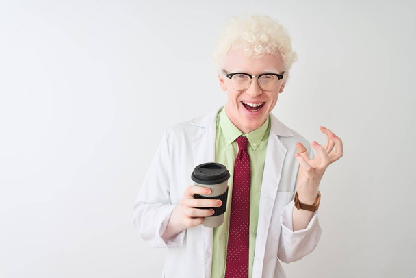 Albino-Wissenschaftler Mann mit Brille trinkt Take-away-Kaffee vor isoliertem weißen Hintergrund sehr glücklich und aufgeregt, Siegerausdruck feiert Sieg schreiend mit breitem Lächeln und erhobenen Händen - Foto, Bild