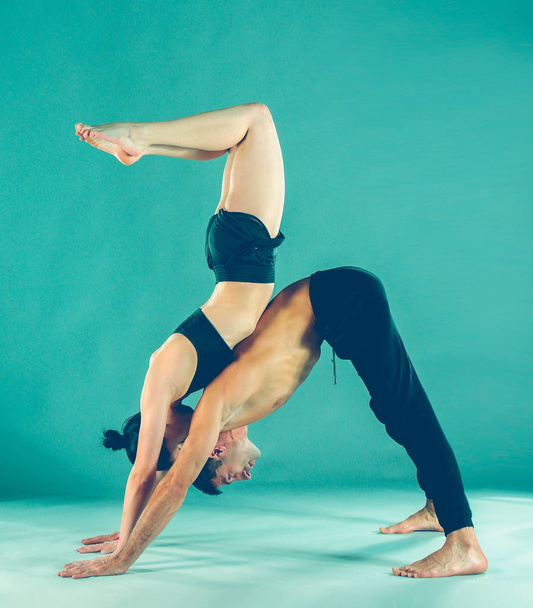 Young couple practicing acro yoga on mat in studio together. Acroyoga. Couple yoga. Partner yoga. - Foto, Imagem