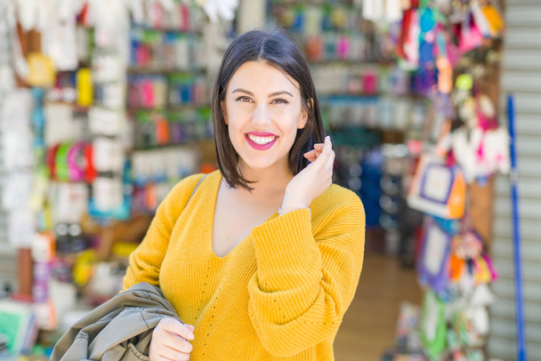 Mooie jonge vrouw die lacht vrolijk lopen door de winkels op straat op een zonnige dag, casual mooi meisje winkelen in de stad - Foto, afbeelding