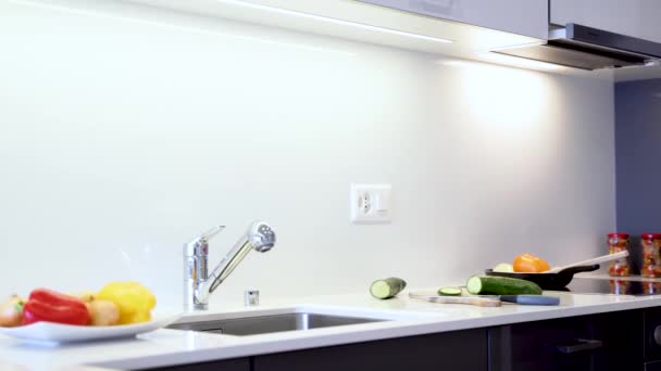 Piano di lavoro della moderna lastra di quarzo. Il bancone della cucina è realizzato in colore bianco con lavello e rubinetto cromati. Armadi da cucina sono realizzati in moderni pannelli piatti neri
. - Filmati, video