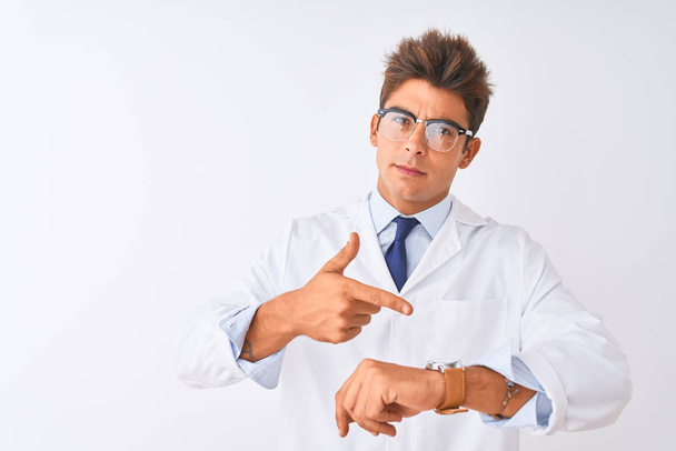 Jonge knappe sciencist man dragen van een bril en vacht over geïsoleerde witte achtergrond in haast wijzend naar kijktijd, ongeduld, boos en boos voor deadline vertraging - Foto, afbeelding