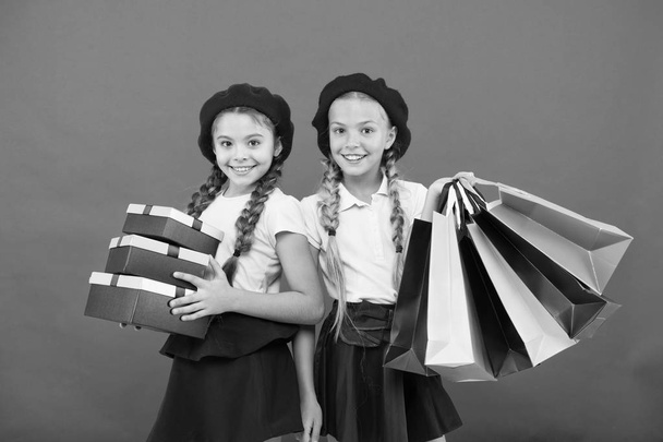Obsessed with shopping and clothing malls. Shopaholic concept. Shopping become fun with best friends. Kids cute schoolgirls hold bunch shopping bags. Children satisfied by shopping red background - Valokuva, kuva