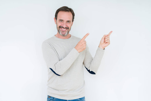 Elegant senior man over isolated background smiling and looking at the camera pointing with two hands and fingers to the side. - Photo, Image
