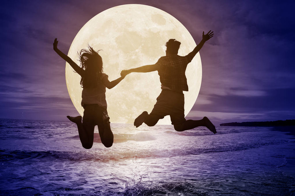 pareja joven saltando en la playa y viendo la luna. Celebra Mi
 - Foto, imagen