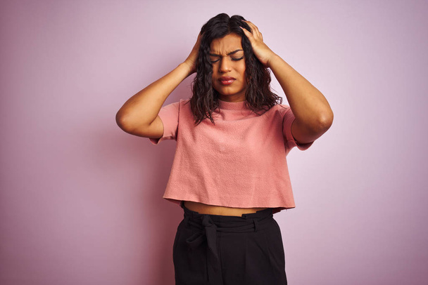 Young beautiful transsexual transgender elegant woman over isolated pink background suffering from headache desperate and stressed because pain and migraine. Hands on head. - Photo, Image