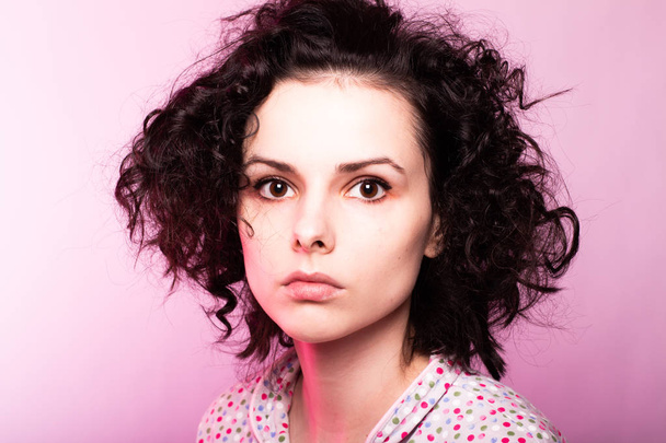 beautiful curly girl in pajamas, pink background - Valokuva, kuva