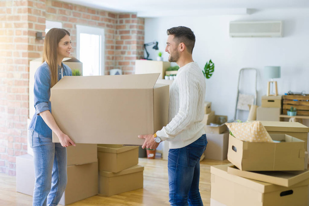 Beautiful young couple moving to a new home, holding big cardboard box - Photo, Image