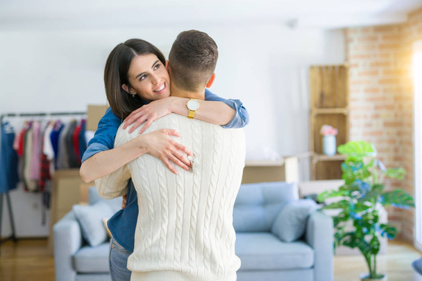 Young couple moving to a new home, hugging in love showing keys of new apartment smiling very happy - Photo, Image