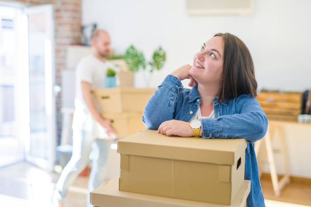 Jovem casal se mudando para novo apartamento, bela mulher que se move caixas de papelão e sorrindo feliz
 - Foto, Imagem