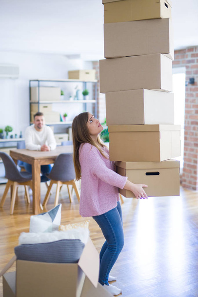 Pareja joven mudándose a una casa nueva, mujer sosteniendo cajas de cartón preocupada por caer en el sobrepeso
 - Foto, imagen