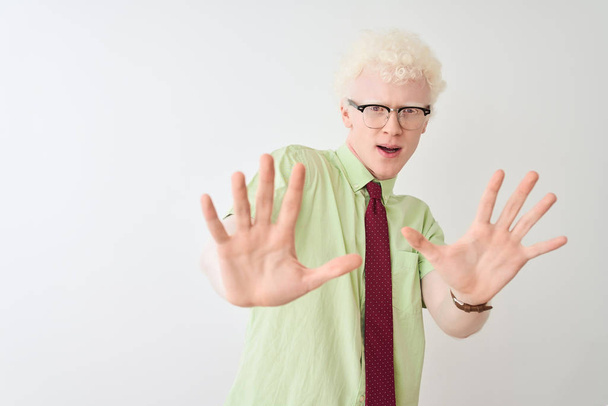Jonge albino zakenman dragen van shirt en stropdas staande over geïsoleerde witte achtergrond bang en doodsangst voor expressie stop gebaar met de handen, schreeuwen in shock. Paniek concept. - Foto, afbeelding