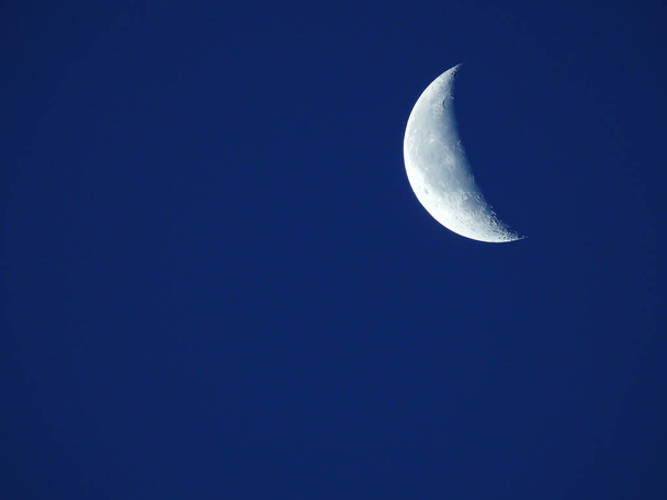 in de blauwe ochtend hemel staat de afnemende kwart maan  - Foto, afbeelding