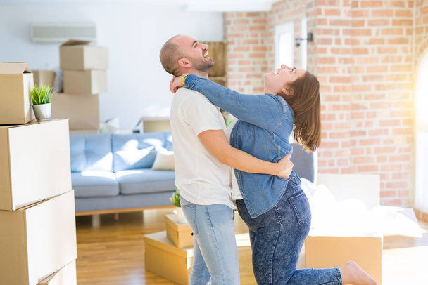 Jeune couple étreignant en amour arround boîtes de carton à la nouvelle maison, célébrant très heureux déménagement dans un nouvel appartement
 - Photo, image