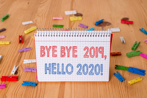 Pisanie pisma ręcznego Bye bye 2019 Hello 2020. Pojęcie rozumieniu pożegnanie z ubiegłego roku i powitanie innego dobrego jeden papier clothespin przypomnienie drewniane puste piętro tło biuro. - Zdjęcie, obraz