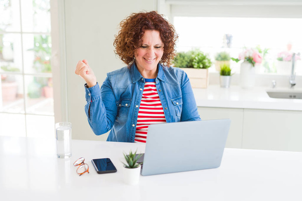 Kıdemli kadın gurur çığlık bilgisayar laptop kullanarak çalışan ve zafer kutluyor ve başarı çok heyecanlı, tezahürat duygu - Fotoğraf, Görsel