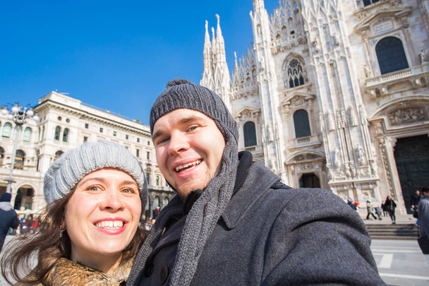 Travel, photographing and people concept - Happy couple taking self portrait in Milano in Duomo square - Photo, Image