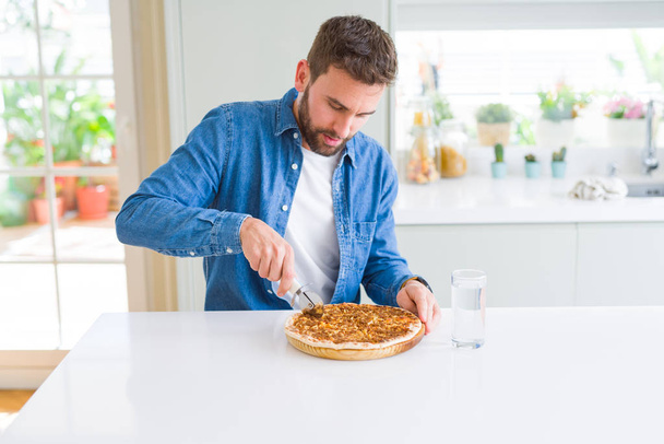 Handsome man cutting a pizza slice at home - Foto, imagen