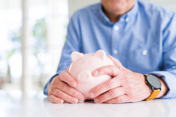 Man holding piggy bank carefully, saving money for retirement - Fotoğraf, Görsel