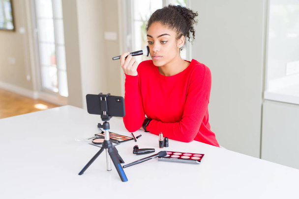 Jovem afro-americana influenciador mulher gravação compõem tutorial com uma expressão confiante no rosto inteligente pensando sério
 - Foto, Imagem