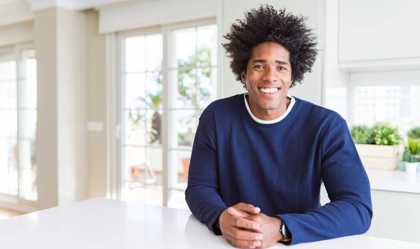 Νέος Αφρικανός Αμερικανός άνθρωπος φορώντας casual πουλόβερ κάθεται στο σπίτι με ένα χαρούμενο και δροσερό χαμόγελο στο πρόσωπο. Τυχερός άνθρωπος. - Φωτογραφία, εικόνα