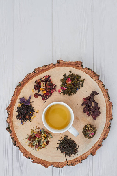 Cup of herbal tea and dry tea on tree slice. - Foto, Imagem