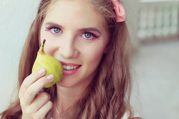 Beautiful girl eating a pear. fashion portrait outdoors - Fotografie, Obrázek