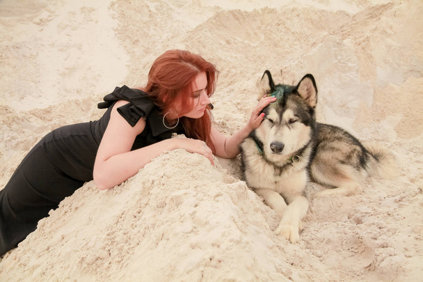 Lustige beste Freunde. glückliche junge Frau spaziert mit großem Hund Malamute in der Wüste - Foto, Bild