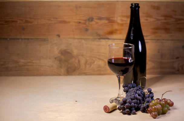 A glass of red wine with grapes and bottle - Fotoğraf, Görsel