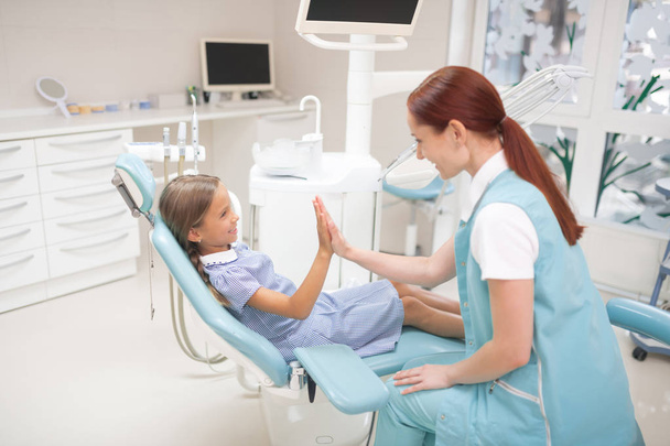 Smiling girl giving high five to her dental therapist - Zdjęcie, obraz