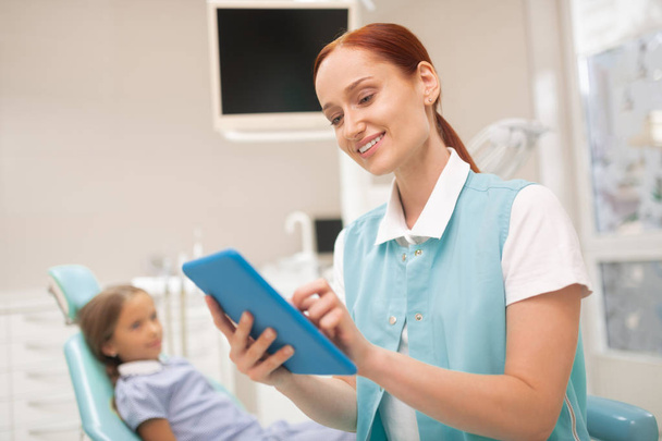 Child dentist smiling while studying clinical record - Photo, image