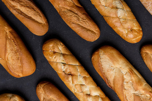 Various bread lie along each other at black background - Foto, Imagem