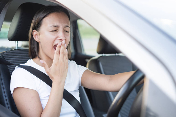 車とあくびを運転する疲れた女性の肖像画 - 写真・画像